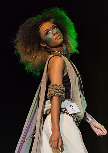 A fashion model with stunning light green hair, striking a pose on the runway