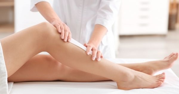 esthetician waxing legs in spa center