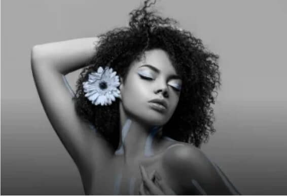 A model with eyes closed, adorned with a stunning blue sunflower in her hair, posing elegantly
