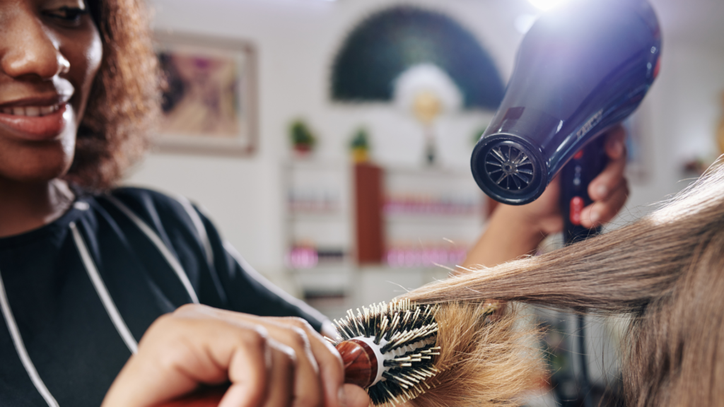 Picture of a hairsylist using a blow dryer to dry a client's hair.