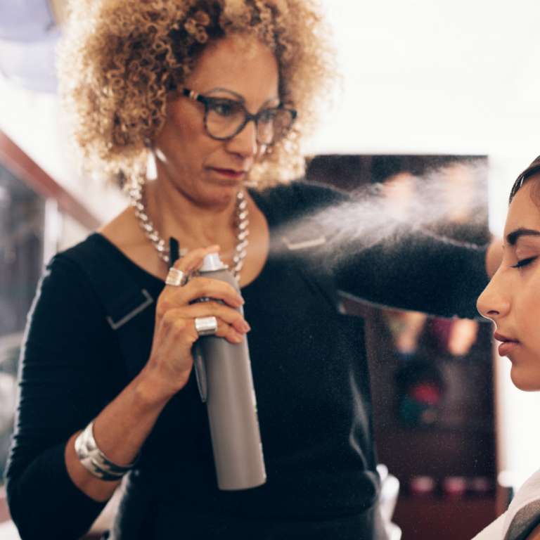 dallas cosmetology student in sprays hairspray on clients hair