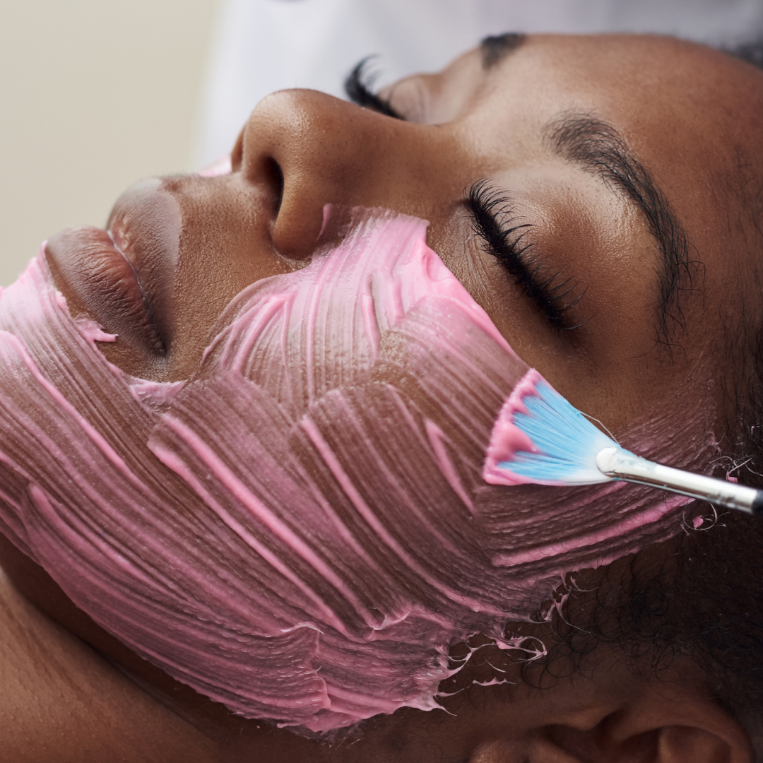esthetician school student applies pink skincare treatment to clients face with a brush