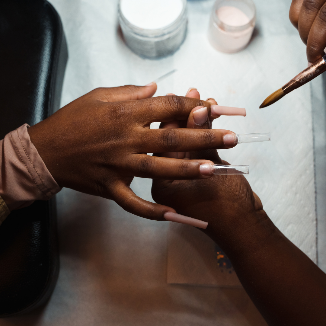 cosmetology student applies nude acrylic nails to client