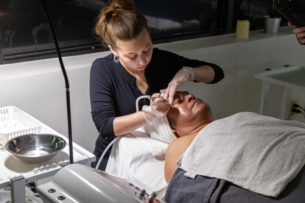 ogle school student giving a facial to a client
