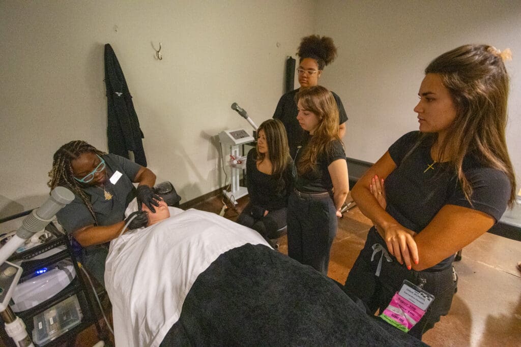 ogle school student giving a facial to a client