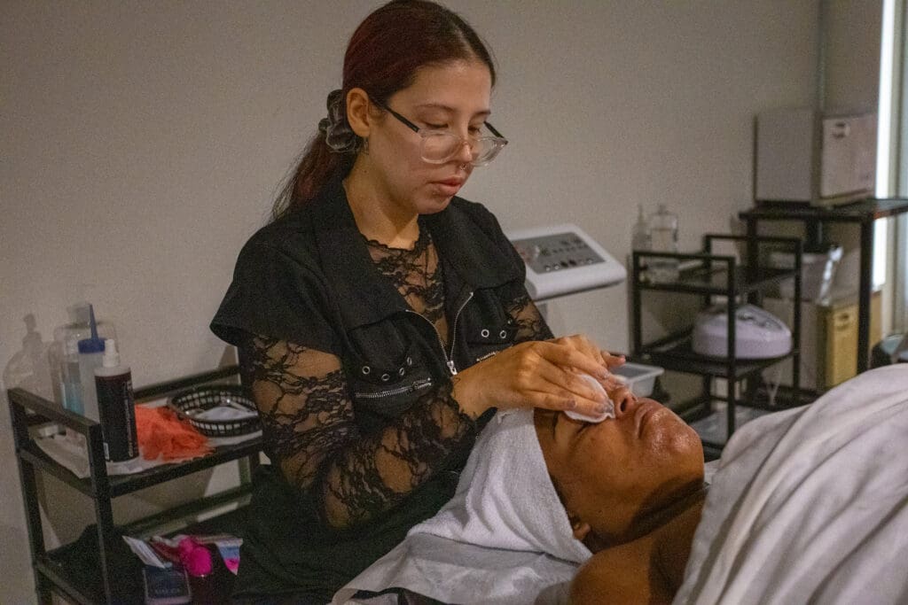 ogle school student giving a facial to a client
