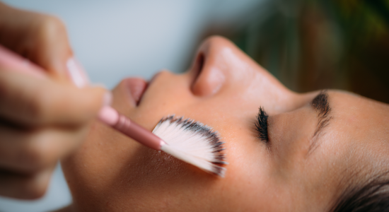 student sweeps brush across clients face to apply skincare treatment
