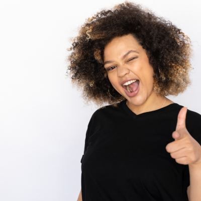 female Esthetician with afro winks at camera with thumbs up
