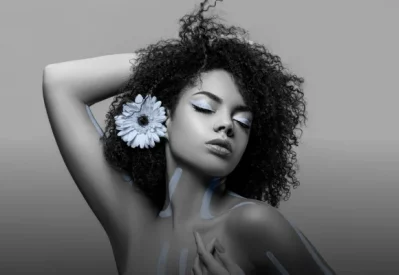 A model with eyes closed, adorned with a stunning blue sunflower in her hair, posing elegantly